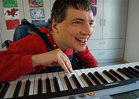 Ein Mann im Rollstuhl spielt auf einem Keyboard.