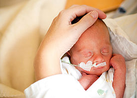 Ein Baby mit Schlauch in der Nase wird im Arm gehalten.