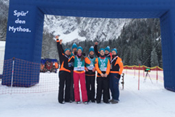 Sieben Personen in Schneekleidung stehen im Schnee und machen Siegerposen.