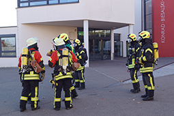 Sechs Feuerwehrleute stehen vor einem Gebäude.