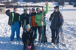 Sechs Personen mit Winterkleidung und Skiern stehen im Schnee.