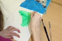 Eine Schülerin malt ein Bild mit einem Pinsel.