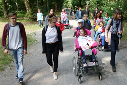 Eine Gruppe Kinder, Jugendlicher und Erwachsener macht einen Spaziergang im Wald.