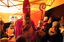 Ein als Bischof Nikolaus verkleideter Mann mit hoher Mütze und Stab steht in einer Menschenmenge und spricht in ein Mikrofon.