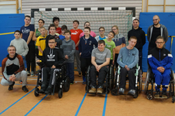 Eine Gruppe Kinder und Jugendlicher sowie einige Erwachsene stehen in einer Sporthalle vor einem Fußballtor.