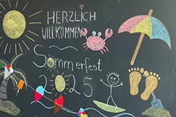 Anlässlich des Sommerfestes 2025 bunt bemalte Tafel, die zusätzlich mit einer bunten Eisgirlande dekoriert ist.