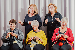 Die Eggenroter Hausfrauen bei einer Bühnenvorstellung. Drei Frauen im Vordergrund stricken.