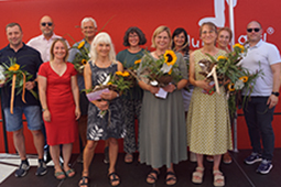 Mitarbeiter-Ehrung beim Abschlussfest der Konrad-Biesalski-Schule. Geschäftsführer Ron Geyer mit Lehrkräften, die teilweise Blumensträuße und Präsente in den Händen halten.