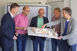 Fünf Männer betrachten das Modell des Kita-Bauprojekts.