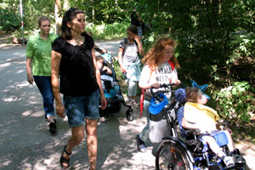 Betreuer und Kinder gehen bei schönem Wetter im Wald spazieren.